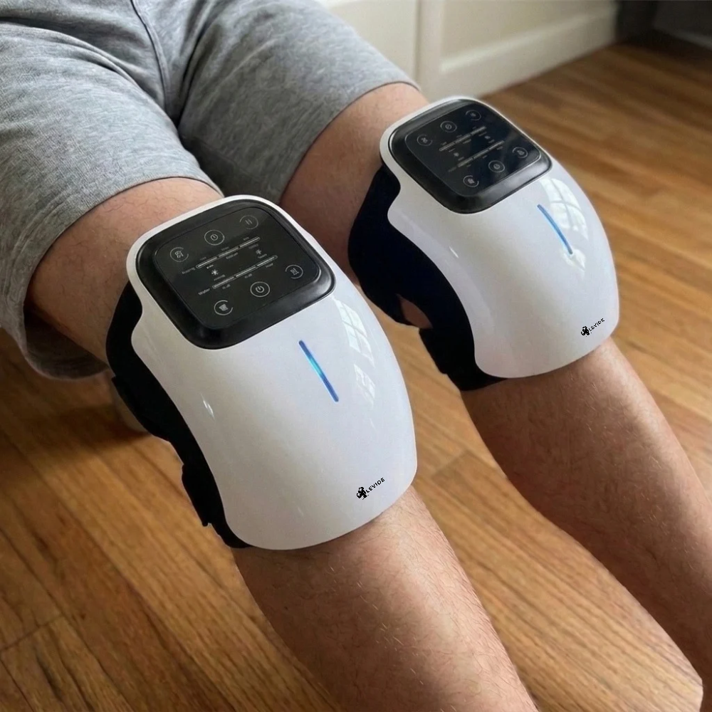 Man on a sofa using two LEVIDE devices, one on each knee